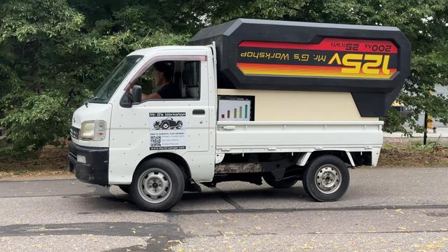 <div><img alt="A small white work truck sitting on a faded road with trees in the background. In its bed is what looks like an enormous drill battery in an upside down position. The "battery" is black with red and yellow stripes. It has the words "125V, 500 Ah, 52 kWh" and "Mr. G's Workshop" emblazoned on the side." class="attachment-large size-large wp-post-image" height="450" src="https://hackaday.com/wp-content/uploads/2026/02/Kei-Truck…-Cordless-_-The-Drill-Battery-EV.jpeg?w=800" style="margin: 0 auto; margin-bottom: 15px;" width="800" /></div><p>Kei trucks are very versatile vehicles, but their stock powerplant can leave a bit to be desired. If you need more power, why not try an electric conversion?</p>
<p>[Ron “Mr. G” Grosinger] is a high school auto shop and welding teacher who worked with his students to <a href="https://www.youtube.com/watch?v=usfm76aCqd4" target="_blank">replace the 40 hp gas motor in this Daihatsu Hijet with the 127 hp of a Hyper 9 electric motor.</a> The motor sits in the original engine bay under the cab and is mated to the stock transmission with a custom adapter plate made from plate steel for less than $150. We really appreciate how they left all the electronics exposed to see what makes the conversion tick.</p>
<p>The faux battery was made by a foam sculptor friend out of urethane foam shaped with a carving knife and then painted. It slides on a set of unistrut trolleys and reveals the 5 salvaged Tesla batt