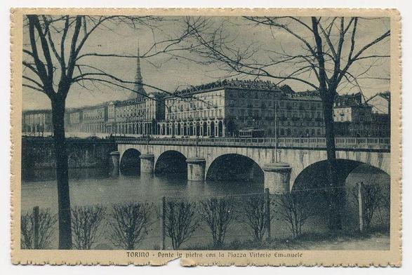 The image depicts a historical postcard showing an old, expansive bridge over turbulent waters with a large building in the background. The architecture of the structure suggests it could be significant or governmental due to its size and prominent design elements like arches on top which are reminiscent of classical Italian styles. This appears to have been captured during winter as the trees are barren and no leaves can be seen, indicating that it's either late fall or early spring before blooming season. The bridge seems robust with several large arched openings allowing passage for what could possibly be trains or pedestrians at a higher level than where water flows underneath.

There is also text on the postcard which reads "Torino - Ponte in pietra con la Piazza Vittorio Emanuele" indicating that this location might be Torino (Turin), Italy, with reference to its famous stone bridge and nearby square. The overall ambiance of the picture gives a historic or possibly even vintage feel.

There is another image referenced at https://images.loener.nl/FerroCandilera/full/6733/673310a089b10e7a26e47037.jpg, which shows a lamppost with the text "ferro candile" suggesting it's made of iron and candles. However, this seems unrelated to the bridge or its surroundings depicted in the main image.

It is worth noting that postcards like these can provide significant cultural insig [...]