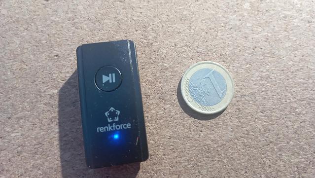 Ein kleines Gerät mit einem Start/Pause Knopf neben einer 1€ Münze zum Vergleich. Das Gerät ist etwas doppelt so groß.