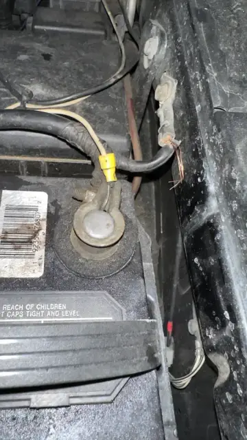 Close-up of a broken battery ground wire at the fender in a Toyota FJ Cruiser, with exposed copper strands.