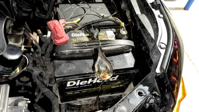 Wide view of a Toyota FJ Cruiser engine bay showing a DieHard battery properly seated and secured with the hold-down bracket.