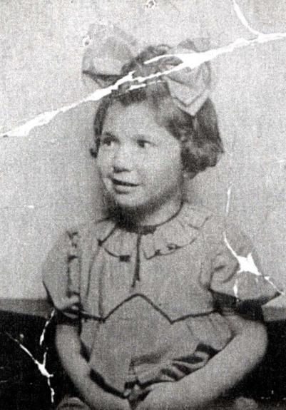 Vintage black-and-white photo of a young girl in a bow-tied outfit, looking to the side with a bright expression.
