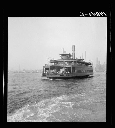 The image is a black-and-white photograph showing a vintage ferry boat on the water, likely in New York City given the context provided. The vessel appears to be a large passenger ferry with multiple decks and several rows of windows along its sides. It has a prominent smokestack at the rear, suggesting it operates using steam power or other combustion engines.

The background reveals an urban skyline across the body of water, indicating that the boat is sailing near a cityscape. The sky appears overcast, casting diffused light on the scene and creating gentle shadows around the ferry's hull. Waves can be seen churning in the wake behind the vessel as it moves through the water.

The photograph has handwritten text at the top right corner with "3-048P1" written across it, which seems to serve as a cataloging or identification code for archival purposes. The overall impression is of an older era of transportation, reflecting on how ferries have historically played a crucial role in connecting cities and regions separated by water bodies.

For more context about this specific ferry boat, the provided link indicates that another image from Dorothea Lange's work shows this vessel with some details identified as "6495b8dbba25398d90c51604." This suggests that the ferry is part of a collection or archive related to transportation history and could be researched further for addit [...]