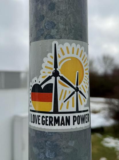 Aufkleber am Laternenmast:“I love german Power“ mit Windrädern und einem Herzen in schwarz-rot-gold