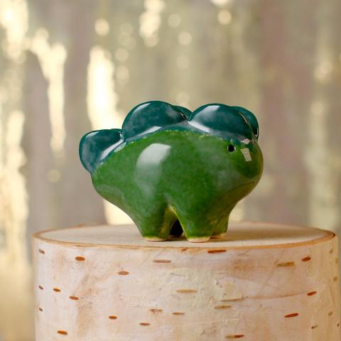 A small green ceramic creature with a light green belly and dark teal back plates.