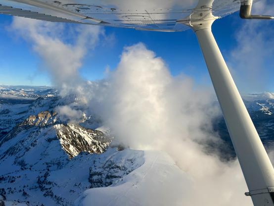 Blick aus dem Flugzeug in die Alpen mit Wolken
