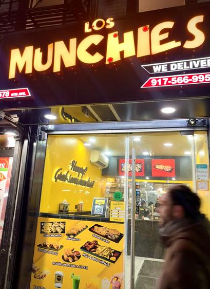 Front entrance of NYC takeout. Very yellow. A man is walking past.