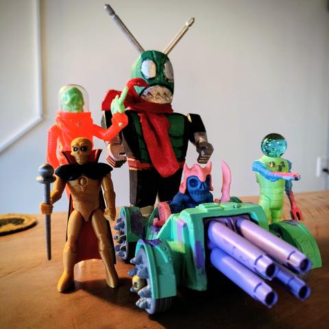 A collection of weird handmade toys, including a large wooden Kamen Rider, the gold bat, a glowing headed robot, and a skeleton goblin driving a tank.