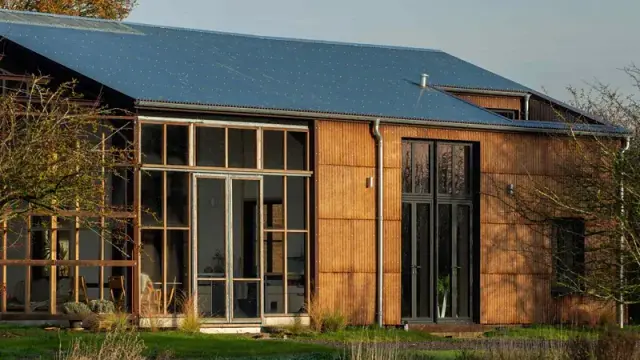 A new house with high windows, hemp fiberboard walls, and a metal (solar paneled?) roof.