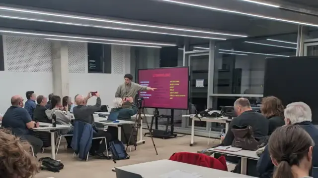 Guillem Carbonell mostrando una diapositiva en una gran pantalla ante decenas de personas.