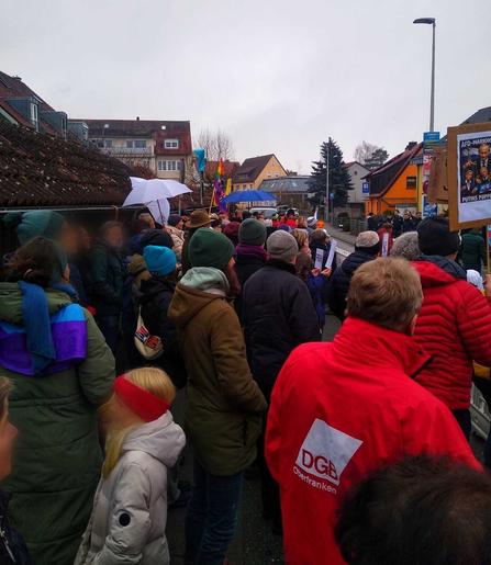 Blick die Gegendemo entlang, Menschen mit bunten Schirmen und Transparenten gegen die AfD, vorne eine Gewerkschafter vom DGB, daneben schaut ein Mädchen in die Gegenrichtung der anderen.