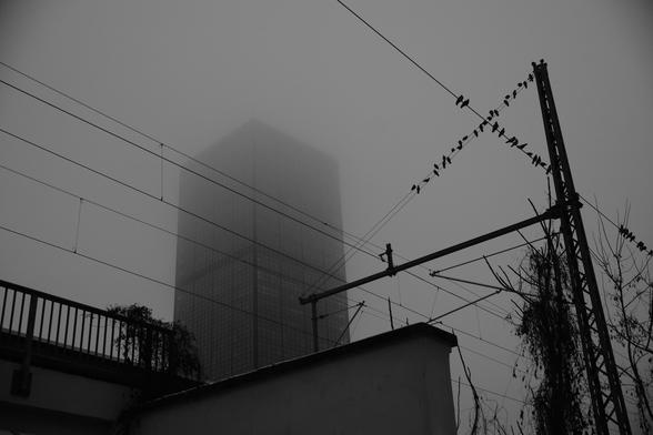 Picture of a high rise partially clouded and a train line