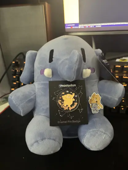 Blue Plushtodon holding 'Live Laugh Federate' pin and a mastodon picker with a QR code linking to joinmastodon.org