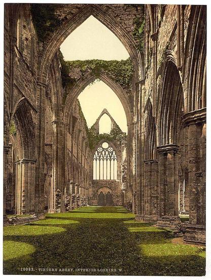 The image portrays an opulent and grandiose abbey interior, specifically Tintern Abbey in England. It features a long nave or central part of the building with intricately designed stone arches that reach towards a vaulted ceiling at both ends. The walls on either side are also adorned with large windows filled with intricate tracery, allowing ample light to flood into the space and illuminate green mossy floors below. Overgrown ivy clings onto parts of the ruins, adding an element of nature reclaiming human-made structures over time.
The Abbey's architecture is reminiscent of medieval Gothic style known for its height, pointed arches, ribbed vaults, and flying buttresses, although those are absent in this ruinous depiction. The sunlight casts warm hues on the stone surfaces, highlighting textures like moss growths and weathered stonework details. The composition exudes a sense of historical reverence and suggests that Tintern Abbey was once an imposing structure with significant spiritual or communal importance.
There's no visible activity within the abbey; it is deserted except for what appears to be ruins left behind by time, suggesting the building has seen better days but still retains much of its former grandeur. The absence of people may also emphasize solitude and reflection in this historic site.