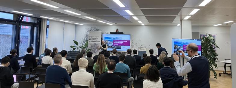 Antoine Bosselut welcomes a group of people in a small event room with screens and plants.