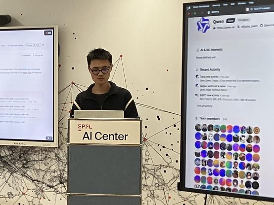 A person presents at the EPFL AI Center, next to a screen showing the Hugging Face platform with a long list of contributors