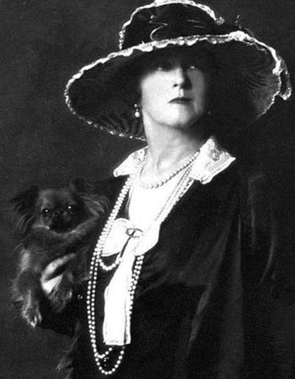 Lucy, Lady Duff-Gordon, wearing a stylish hat and holding a small dog.