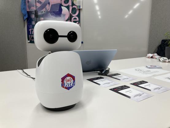 A robot with some name tags and laptop in front of a poster