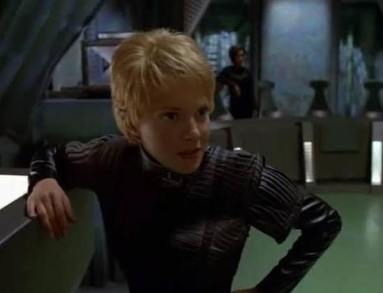 Close up of Kes in a black leather outfit and looking irritated