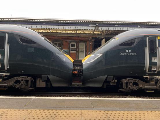 Green trains coupled. The shape of the trains and open coupler housing looks a bit like they are kissing.
