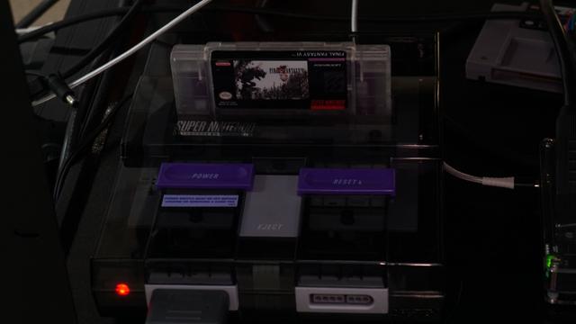 The custom shelled Super Nintendo running a custom cart of FF6 with the decensored Ted Woolsey translation in a clear acrylic shell.