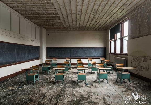 abandoned classroom with tiny blue chairs with attached desk tables
