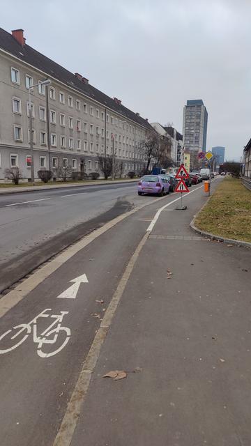 Ein Radweg und ein Gehweg daneben. Auf dem Schild steht Achtung Bauarbeiten und spurverengung.