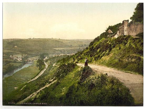 This image depicts a scenic view from Castle Hill in Totnes, South Hams district of Devonshire. The vantage point is elevated on the hillside overlooking lush greenery and farmland sprawling down to what appears to be Torrington Bridge over River Dart below.

The focus features an individual standing at a high point along a winding path leading up to or descending from Castle Hill's edge, possibly indicative of early 20th-century attire. The castle on the hilltop has a fortified look with walls and towers typical for defensive purposes in historical military architecture found within England during this period.

The overall tone is warm due to what seems like sunlight casting an orange hue across the landscape, suggesting that it could be late afternoon or sunset hours.

Notably absent are modern-day structures, which lends credence to its age as a historic depiction.