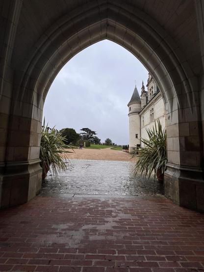 Archway framing a turreted castle appearing ti the right