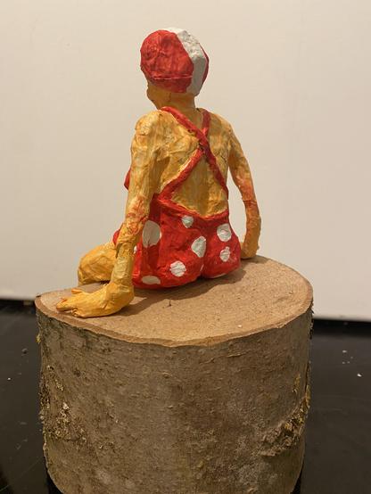 Sitzende weibliche Figur im roten Badeanzug mit weißen Punkten aus Papiermaché