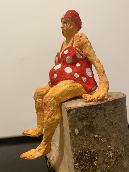 Sitzende weibliche Figur im roten Badeanzug mit weißen Punkten aus Papiermaché