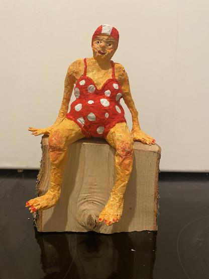 Sitzende weibliche Figur im roten Badeanzug mit weißen Punkten aus Papiermaché