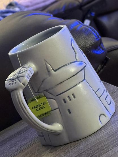 A mug with Tatooine buildings on it and the Millennium Falcon in the handle. There’s a green tea tag hanging on it.