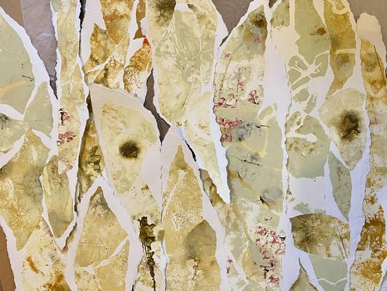 Een stapel papieren snippers (armgrootte). Daarop collages van monoprints in de kleuren Napels geel/groen, terra, sienna en mixen.