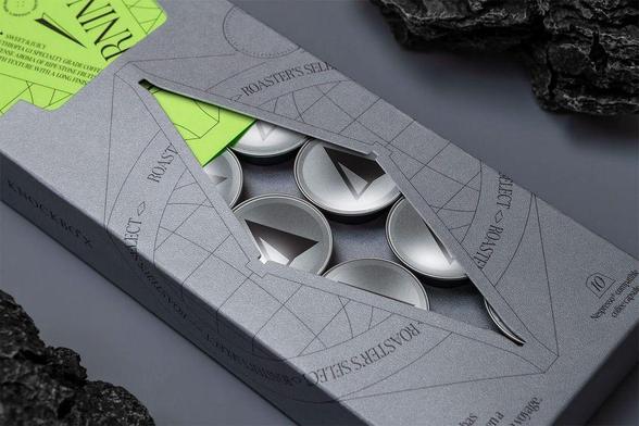 A sleek gray box with a geometric design, revealing silver tin containers inside, complemented by a vibrant green label.