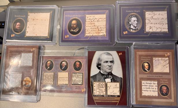 Seven relic trading cards. The overhead light is on, making some reflective glare.