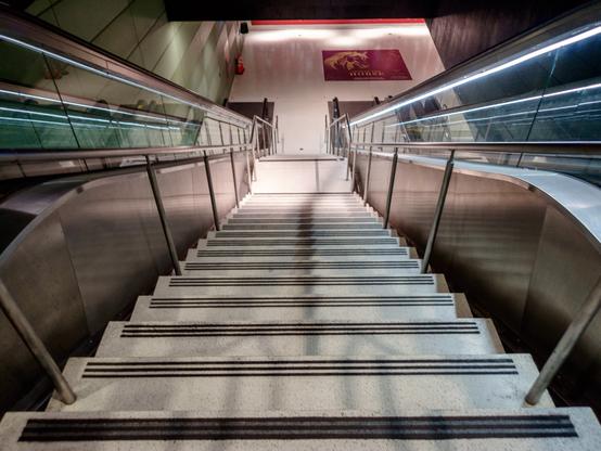 Looking down a stairway in between two escalators in a light rail station