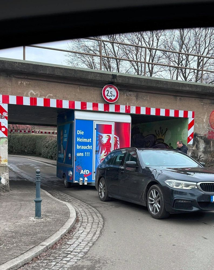 Ein Anhänger mit AFD Werbematerial beklebt, steckt in einer Unterführung fest.