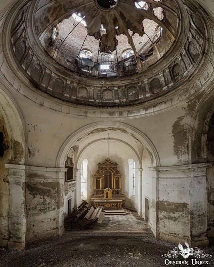Interior of a dilapidated Romanian mausoleum featuring a collapsed dome exposing the sky. A golden altar contrasts with crumbling walls and debris.