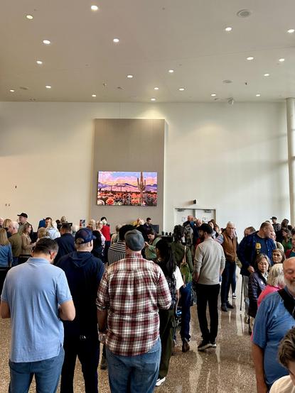 Another view of ticket line. Very Tucson lighted sign with desert view painting with cactus and mountains.