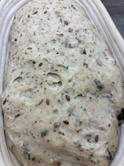 Seeded sourdough in a batard banneton showing seeds, seaweed and herbs