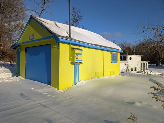 a normal colour picture from my phone of the yellow and blue garage and white houseboat