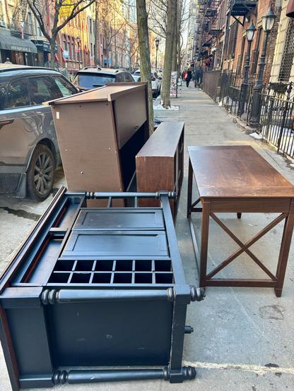 NYC sidewalk, three or four pieces of furniture. A black sideboard with drawers and wine storage.
