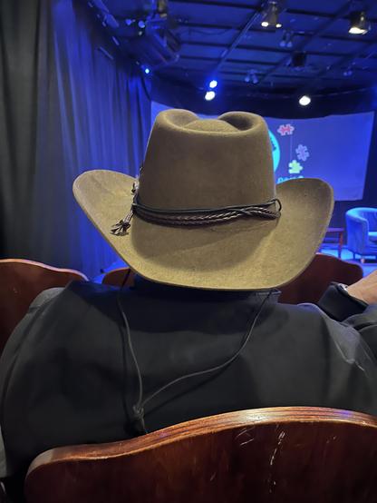 Photo of the back of an uncouth man wearing a cowboy hat at the theater.