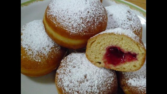 Berliner, ein frittierter Teigling.mit Fruchtmarmeladefüllung, erkennbar an beiden seiten die goldbraun sind, und dem.Puderzucker oben drauf. Diese sind elastisch und weich.