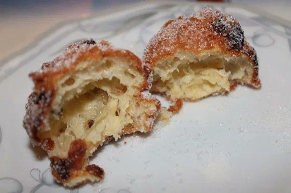 Krapfen, ein frittierter Eierteig, hier mit Rosinen, welcher innen hohl ist ubd außen knusprig.