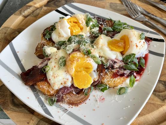 A square plate on a cutting board. to the top right is some cutlery.

the plate is topped with the following, three times, arrayed in a triangular shape.
a hash brown. a slice of short-cut bacon. a dollop of beetroot relish. an egg poached in the shell to 64 degrees celsius. a sprinkle of chopped spring onion. some grated cheddar cheese.