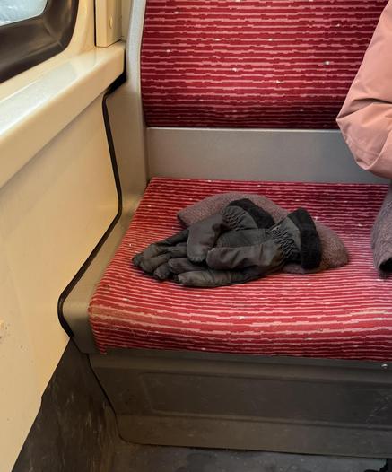 Auf einem U-Bahn-Sitz liegen Mütze und Handschuhe, daneben sitzt jemand. (Sie hat dran gedacht…)
