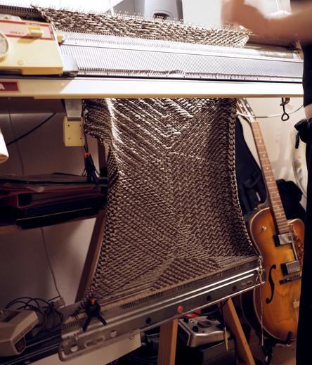 A knitted piece hanging from a knitting machine