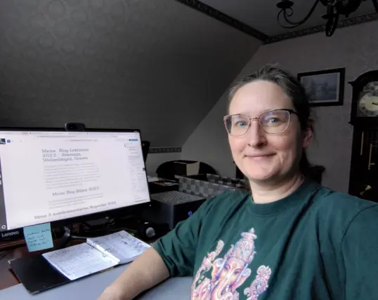 Selfie einer lächelnden Frau an einem Arbeitstisch, auf dem Computerbildschirm ist dieser Beitrag über Blog-Lektionen 2025 geöffnet